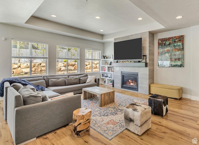 7518 S 5720 W, West Jordan, UT 84081 - living area featuring a tray ceiling, a wealth of natural light, a tiled fireplace, and wood finished floors