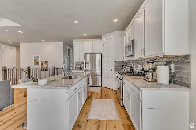 7518 S 5720 W, West Jordan, UT 84081 - kitchen with a sink, stainless steel appliances, light wood-type flooring, white cabinetry, and backsplash