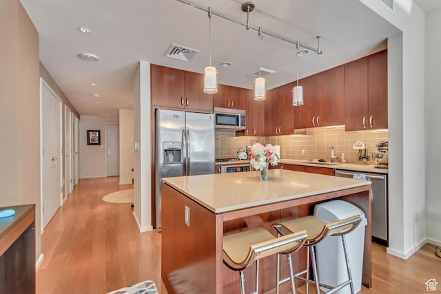 35 E 100 S Unit 204, Salt Lake City, UT 84111 - kitchen with light wood-style floors, visible vents, appliances with stainless steel finishes, a kitchen island, and tasteful backsplash