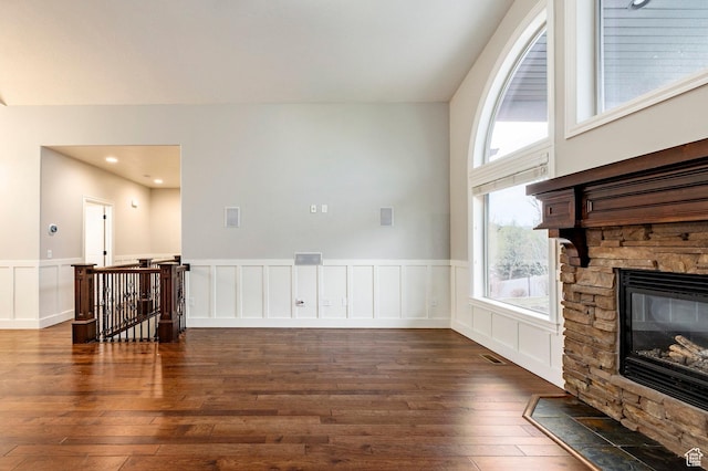 3440 Greenfield Cir, Mountain Green, UT 84050 - unfurnished living room with dark wood-style flooring, a stone fireplace, visible vents, and a wainscoted wall