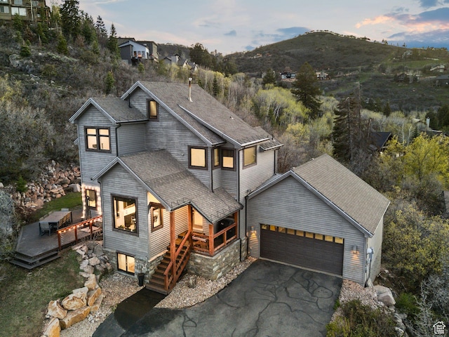 7515 Stagecoach Dr, Park City, UT 84098 - contemporary house featuring an attached garage, a deck with mountain view, driveway, roof with shingles, and stairway