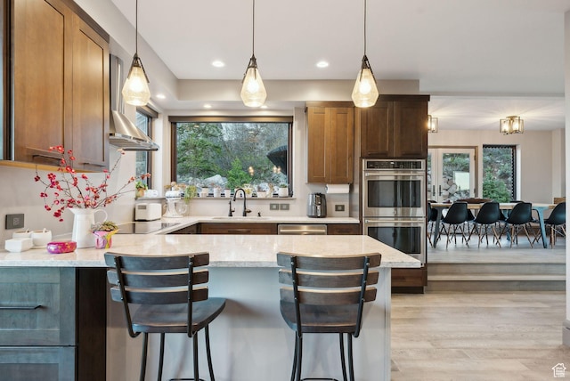 7515 Stagecoach Dr, Park City, UT 84098 - kitchen featuring stainless steel appliances, light stone counters, light wood finished floors, a peninsula, and decorative light fixtures