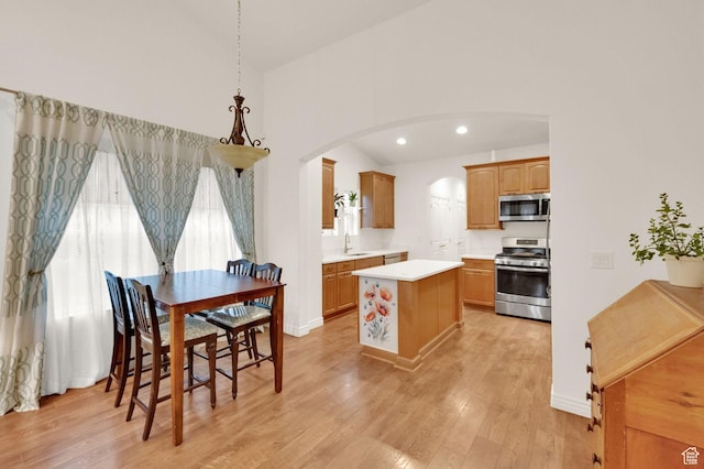 10557 S Pipestone Way S, Jordan, UT 84009 - kitchen with stainless steel appliances, a center island, light wood finished floors, arched walkways, and light countertops