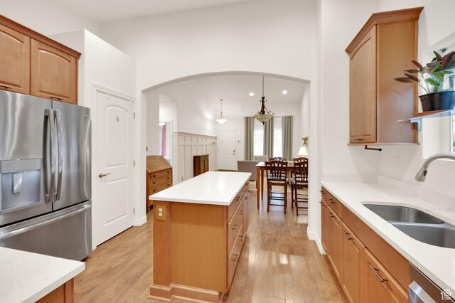 10557 S Pipestone Way S, Jordan, UT 84009 - kitchen featuring a sink, stainless steel appliances, light wood-type flooring, arched walkways, and a kitchen island