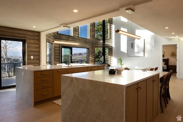 7370 N Buckboard Dr, Park City, UT 84098 - kitchen with a spacious island, modern cabinets, rustic walls, a sink, and light wood-style floors