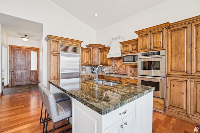 12221 Ross Creek Dr Unit 137, Kamas, UT 84036 - kitchen featuring a sink, brown cabinets, backsplash, custom range hood, and appliances with stainless steel finishes