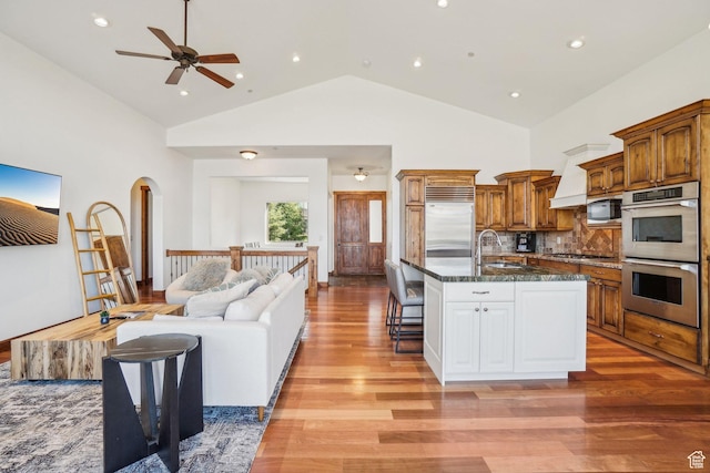 12221 Ross Creek Dr Unit 137, Kamas, UT 84036 - kitchen featuring a breakfast bar area, light wood finished floors, open floor plan, brown cabinets, and appliances with stainless steel finishes