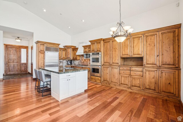 12221 Ross Creek Dr Unit 137, Kamas, UT 84036 - kitchen with stainless steel appliances, a breakfast bar, high vaulted ceiling, light wood finished floors, and a notable chandelier