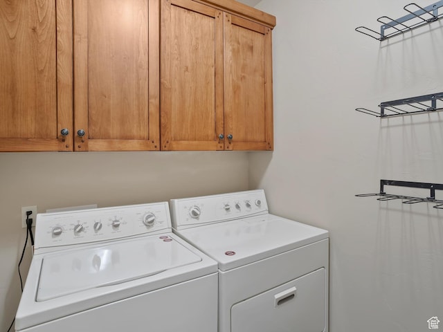 clothes washing area featuring cabinet space and washer and clothes dryer