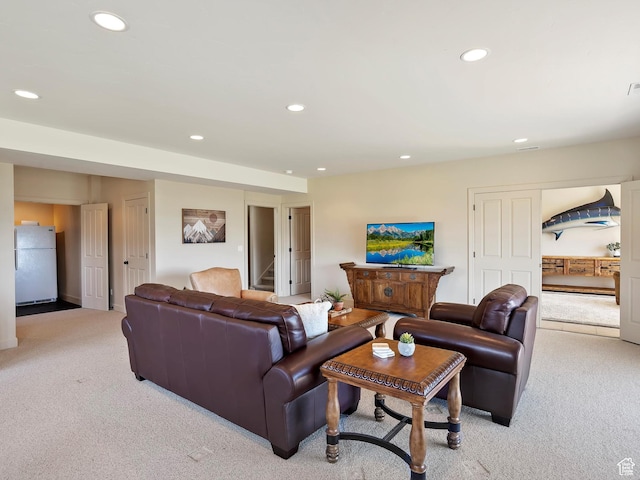 living area featuring stairs, recessed lighting, and light colored carpet