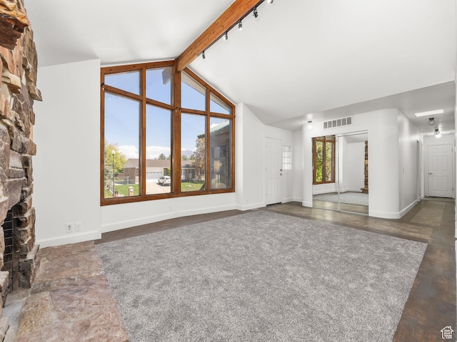 unfurnished living room with visible vents, baseboards, lofted ceiling with beams, and a fireplace