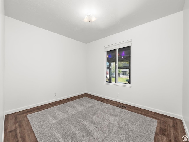 empty room with visible vents, baseboards, and dark wood-type flooring