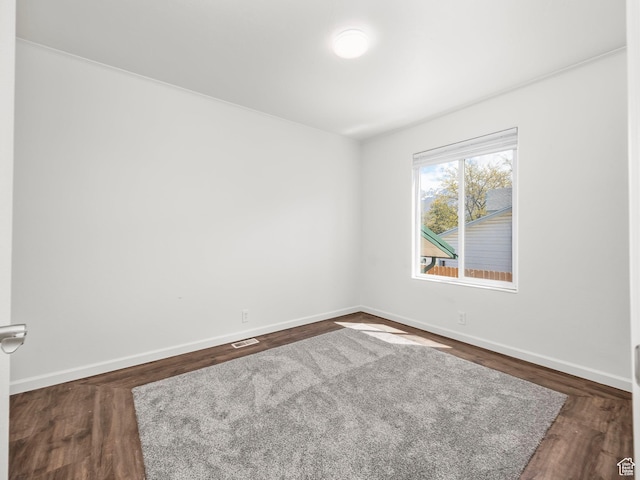 spare room featuring dark wood-type flooring, baseboards, and visible vents