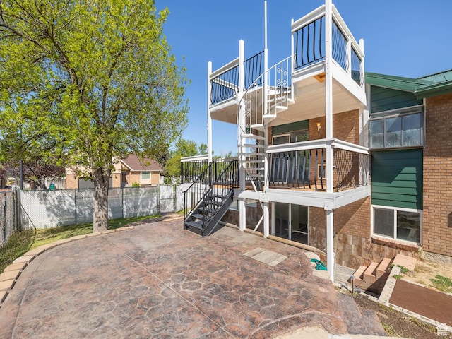 back of property featuring a patio area, stairway, brick siding, and fence