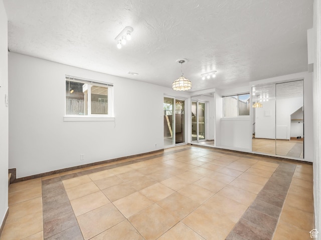 tiled empty room with a textured ceiling and baseboards