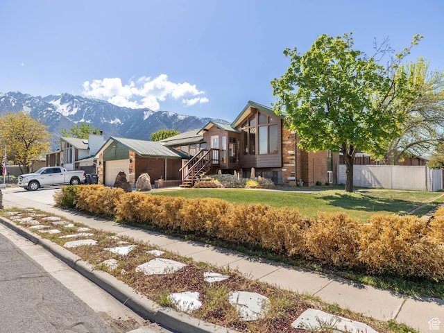 view of home's exterior with fence, a garage, a mountain view, and a lawn