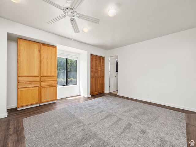 unfurnished bedroom featuring a closet, baseboards, ceiling fan, and dark wood-style floors