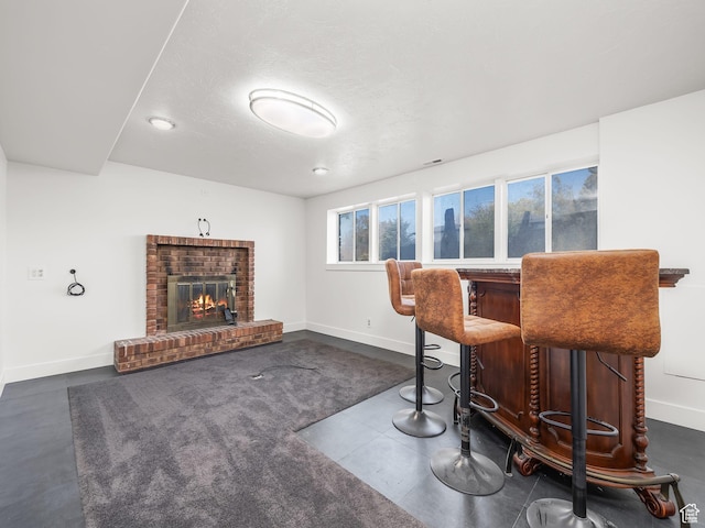 bar featuring baseboards, a brick fireplace, a bar, and recessed lighting
