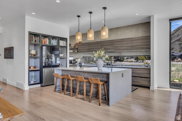 846 E 270 S, Kamas, UT 84036 - kitchen with modern cabinets, light wood-style floors, a kitchen island with sink, light countertops, and a breakfast bar area