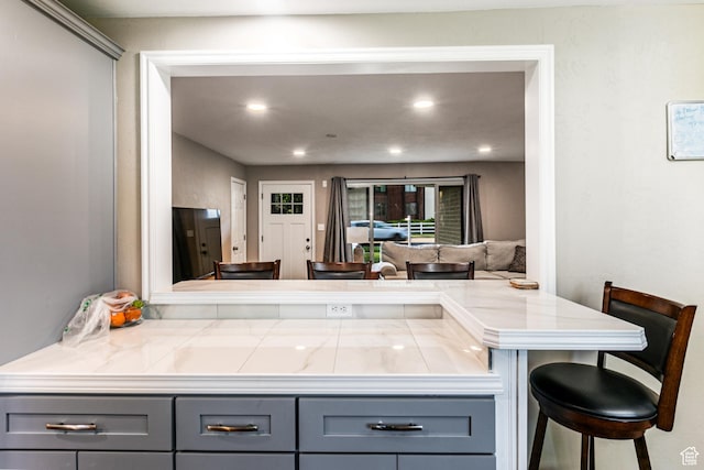 kitchen featuring a peninsula, gray cabinetry, a kitchen breakfast bar, and recessed lighting