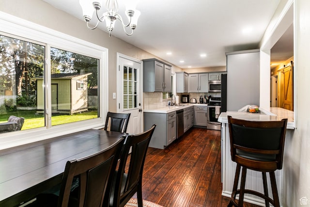 kitchen featuring a notable chandelier, light countertops, gray cabinetry, a sink, and stainless steel appliances