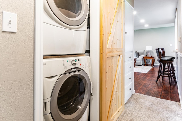 laundry area featuring stacked washer and dryer, laundry area, recessed lighting, and a textured wall