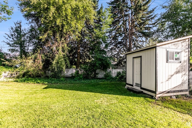 view of yard featuring an outbuilding, a storage shed, and fence private yard