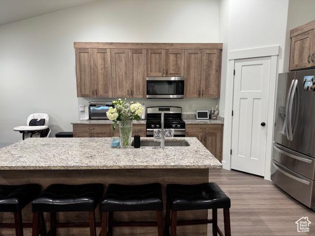 88 E 970 N, Santaquin, UT 84655 - kitchen featuring stainless steel appliances, a kitchen breakfast bar, wood finished floors, and light stone countertops