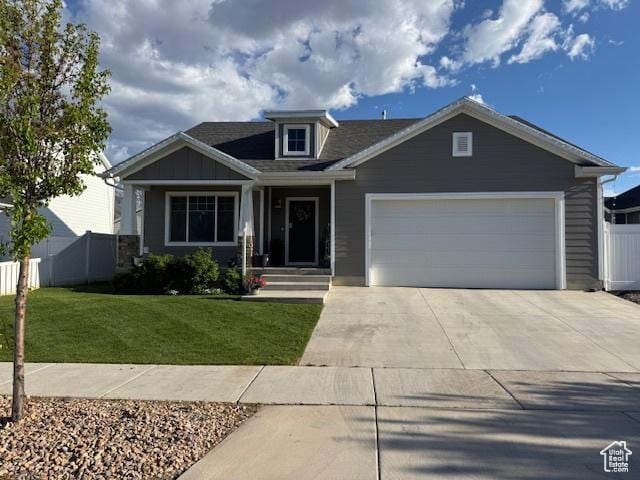 craftsman-style house featuring concrete driveway, a front yard, an attached garage, and fence