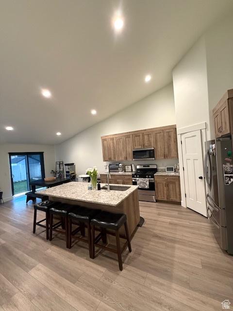 88 E 970 N, Santaquin, UT 84655 - kitchen with light wood finished floors, a kitchen bar, a kitchen island with sink, light countertops, and appliances with stainless steel finishes