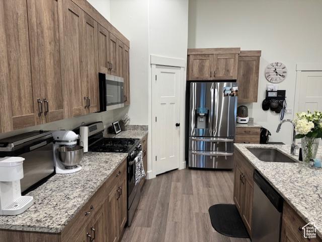 88 E 970 N, Santaquin, UT 84655 - kitchen with wood finished floors, a sink, brown cabinetry, light stone countertops, and appliances with stainless steel finishes