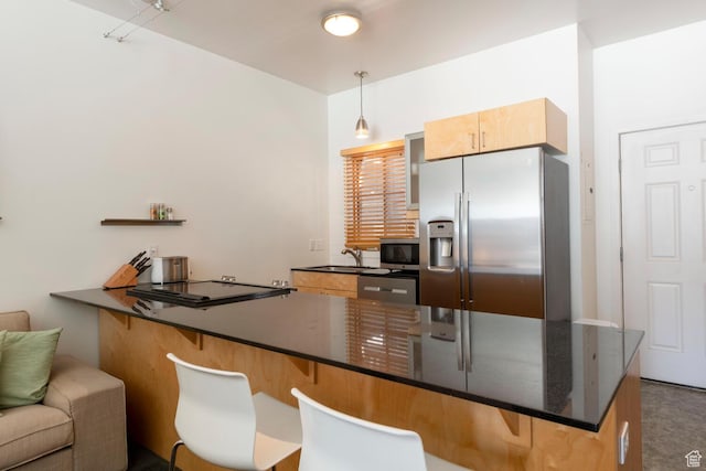 228 E 500 S Unit 301, Salt Lake City, UT 84111 - kitchen featuring a sink, a peninsula, a kitchen breakfast bar, pendant lighting, and appliances with stainless steel finishes