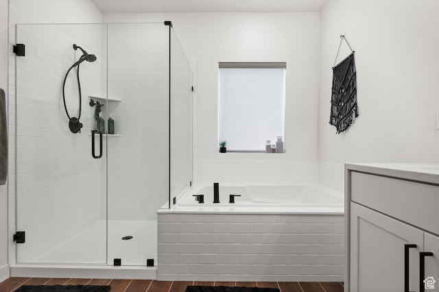 full bath with vanity, a shower stall, a bath, and wood finished floors