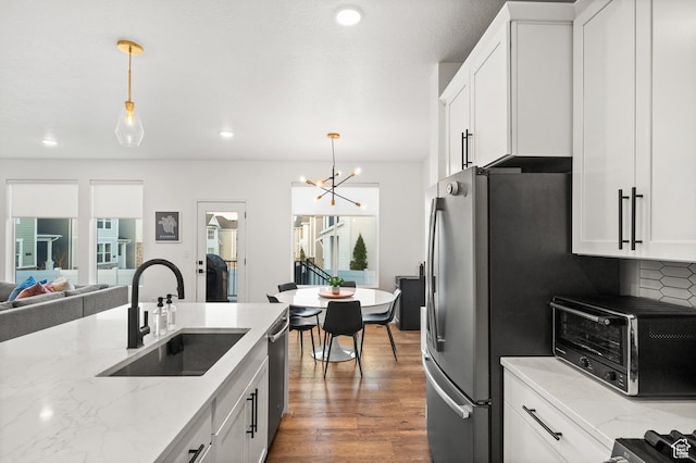 kitchen featuring a sink, an inviting chandelier, decorative light fixtures, and white cabinets