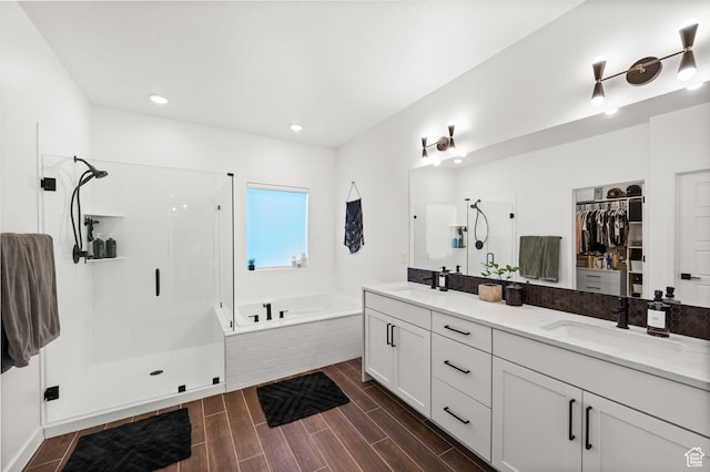 full bathroom featuring a sink, a stall shower, a spacious closet, double vanity, and a garden tub