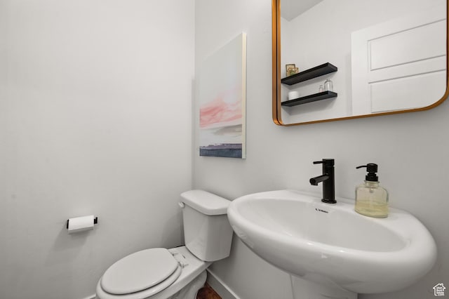 half bathroom featuring a sink, toilet, and baseboards