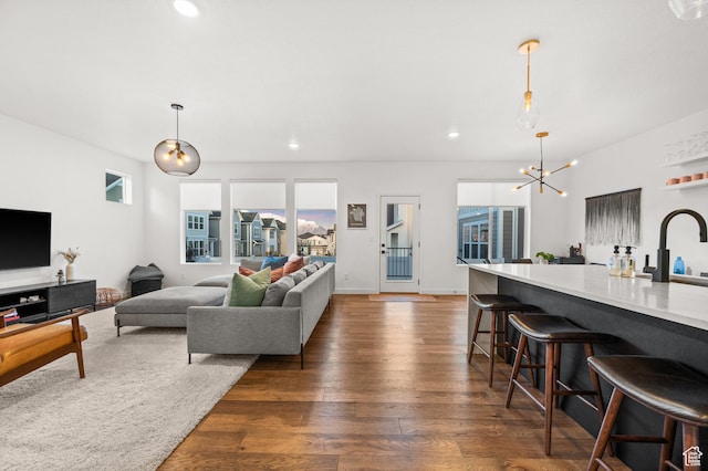 living area featuring a chandelier, dark wood-type flooring, and recessed lighting