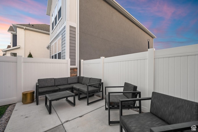 patio terrace at dusk featuring a fenced backyard and an outdoor living space