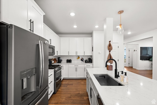 kitchen featuring a sink, stainless steel appliances, white cabinets, dark wood finished floors, and backsplash