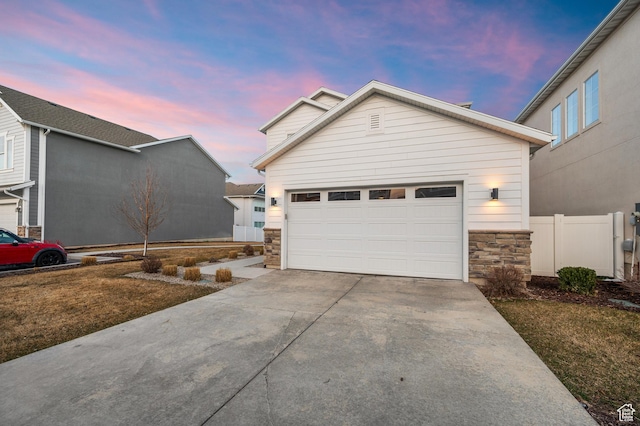 view of front of house with fence, concrete driveway, a garage, and stone siding