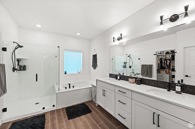 bathroom with a stall shower, a bath, a sink, double vanity, and a walk in closet
