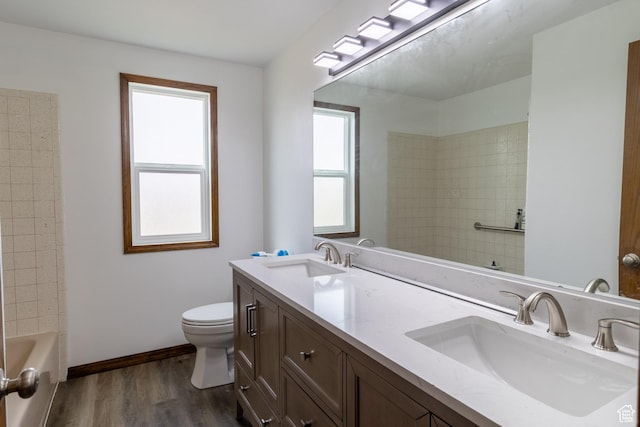 bathroom with double vanity, toilet, wood finished floors, and a sink