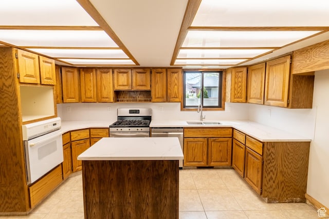 kitchen featuring brown cabinetry, light tile patterned flooring, a sink, a kitchen island, and stainless steel appliances