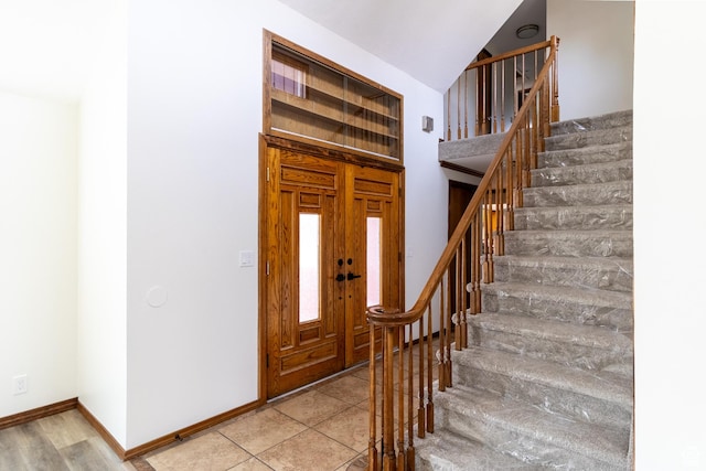 foyer entrance featuring stairway and baseboards