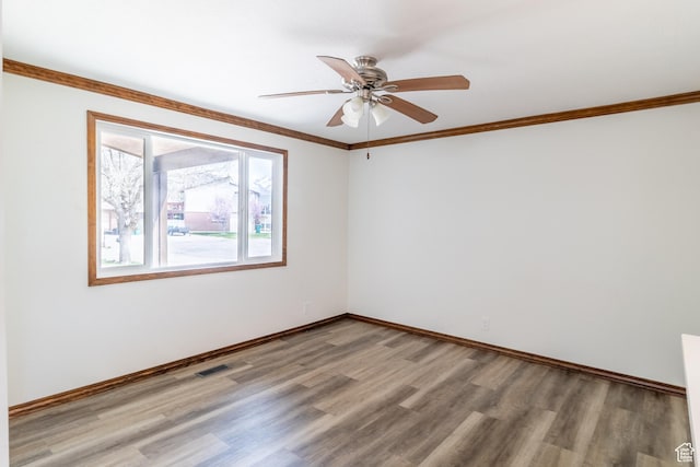 spare room with a ceiling fan, baseboards, light wood-style flooring, and crown molding