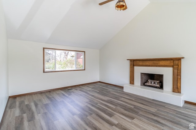 unfurnished living room with lofted ceiling, wood finished floors, ceiling fan, baseboards, and a tile fireplace