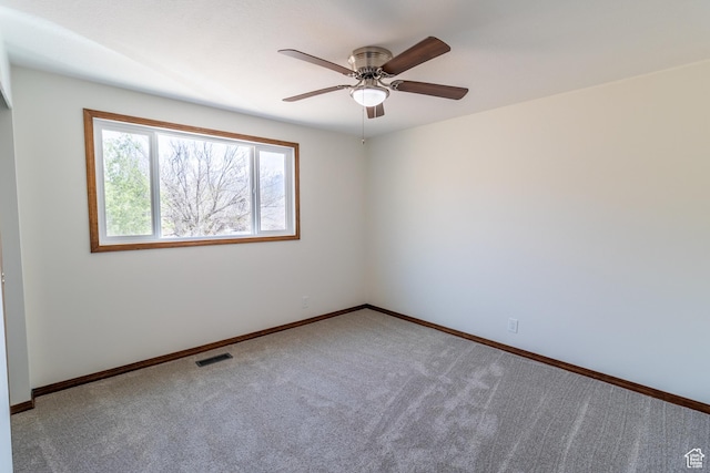 carpeted spare room featuring baseboards, ceiling fan, and visible vents