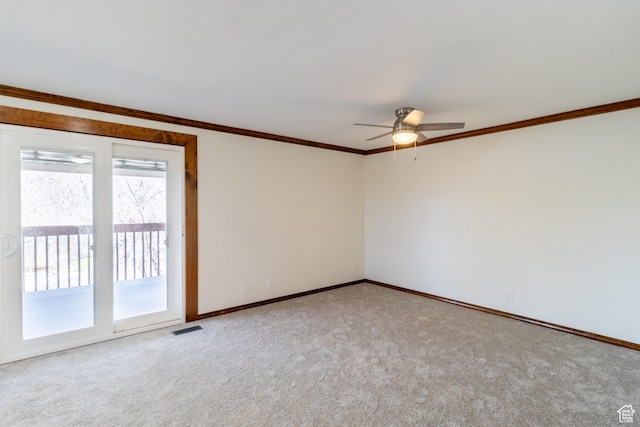 empty room with a ceiling fan, carpet flooring, crown molding, and baseboards