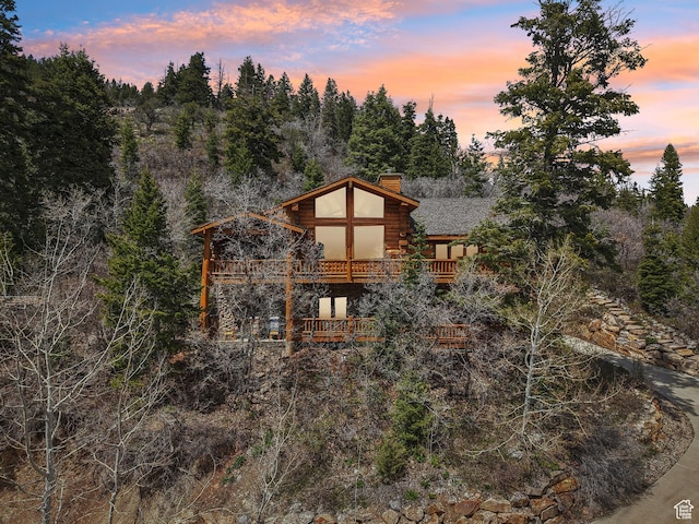 exterior space with a chimney, log exterior, and a balcony