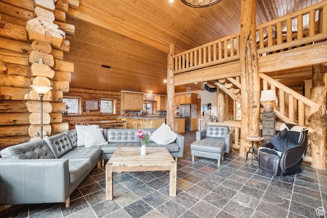 living area with a high ceiling, rustic walls, stone tile floors, and wood ceiling